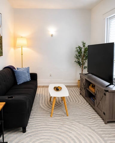Light sitting room with gray chaise lounge, round side table, and ladder shelf