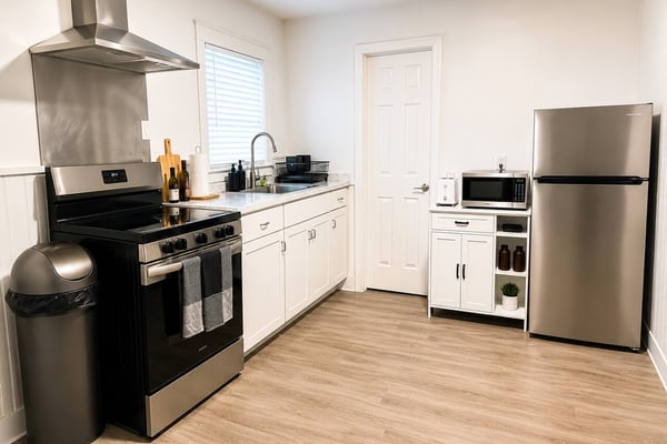 Modern kitchen with white cabinetry, stainless steel appliances, gas range, and wood-look flooring